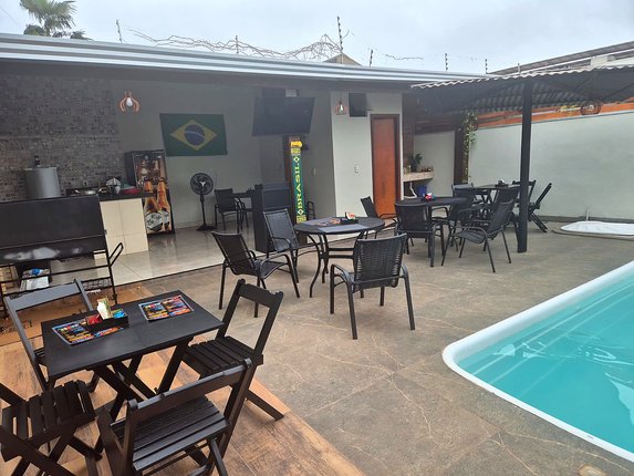 Espaço gourmet coberto com mesas e churrasqueira