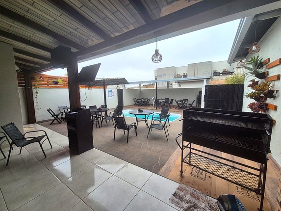Ambiente com piscina, mesas e cobertura para hóspedes